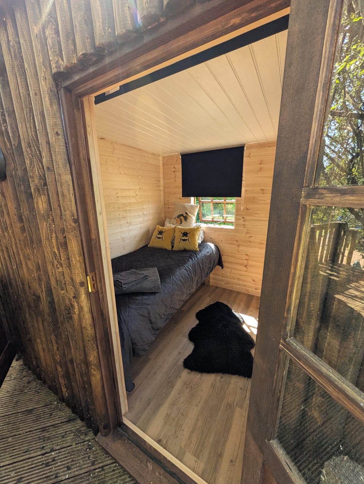 Cosy treehouse bedroom with pine cladding and oak-effect flooring by Cover It Building